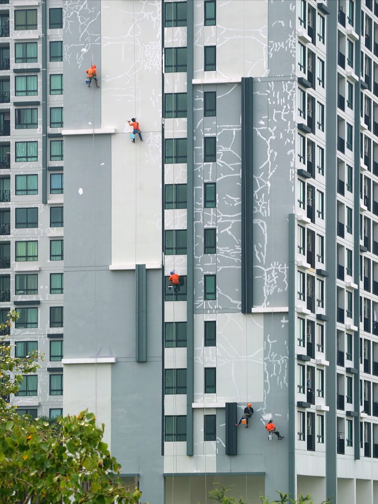 five industrial climbing workers painting facade high residential building